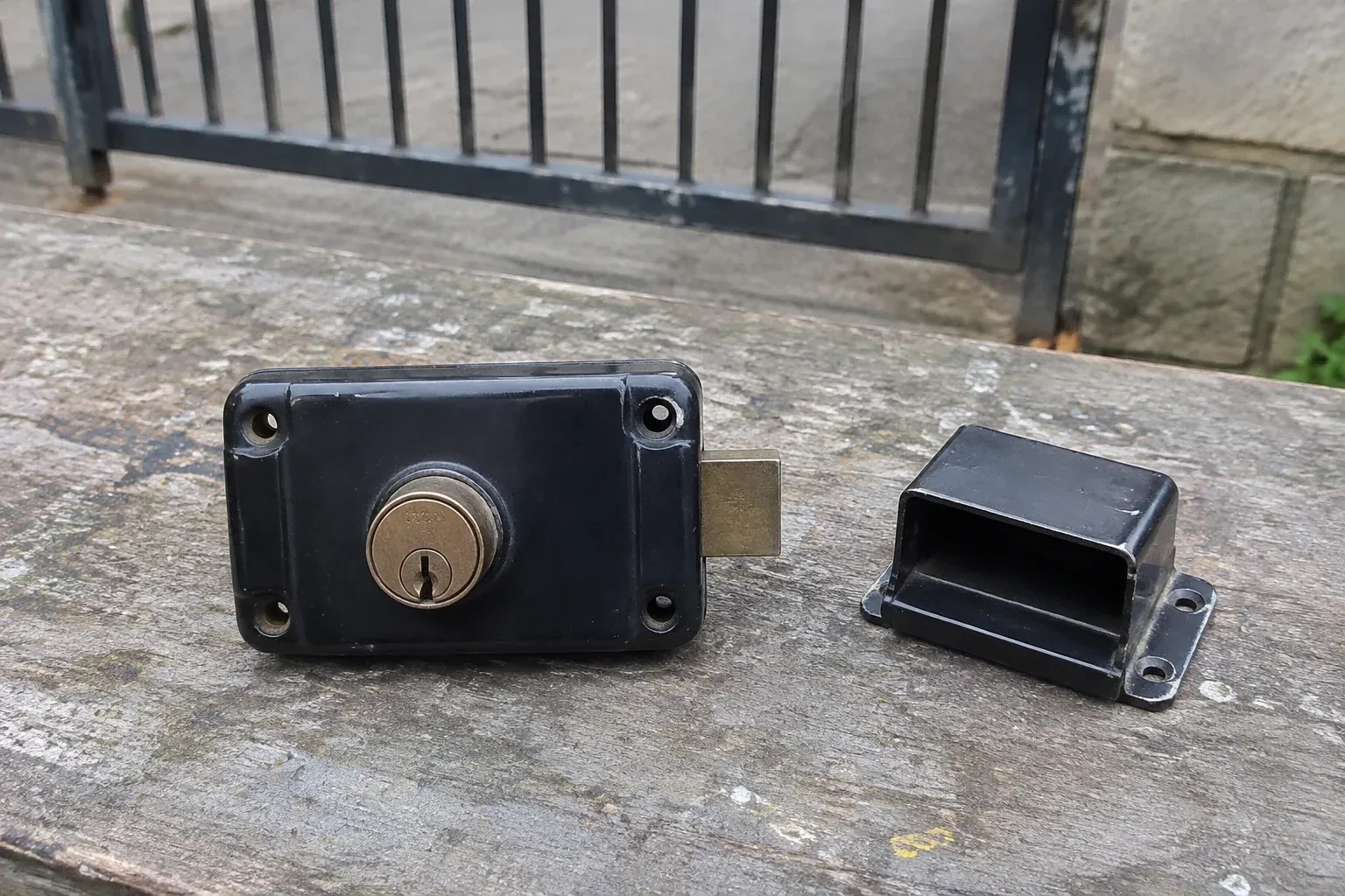 Detached rim gate lock and separate box keeper on an outdoor workbench. — Gate & Building Entry Locks, Oro-Medonte